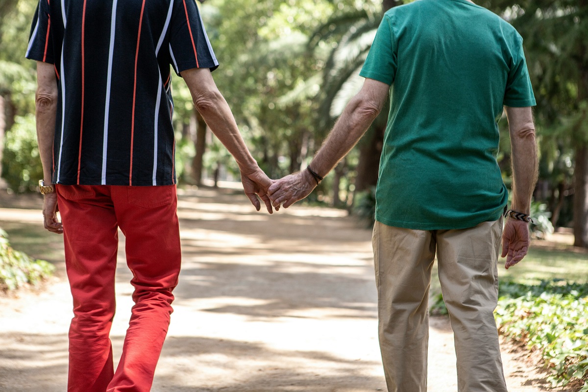 elderly man and his son walking hand in hand at a park