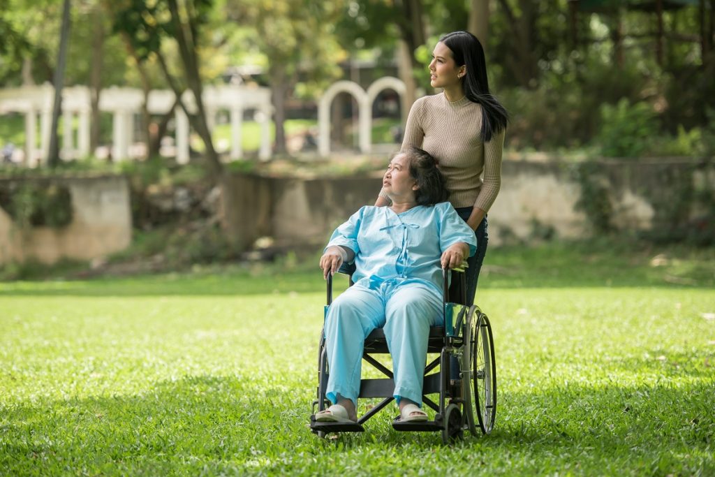 woman pushing a person with disability in a wheelchair